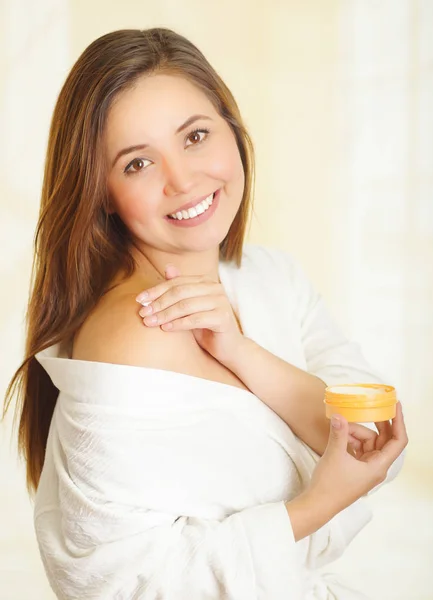 Beautiful smiling young woman adding a cream body over her shoulder — Stock Photo, Image