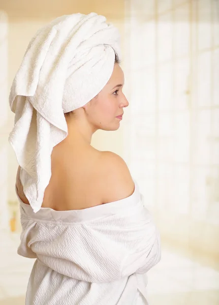 Mooie lachende jonge vrouw met een witte handdoek die betrekking hebben op haar hoofd is poseren met een lichaam handdoek — Stockfoto