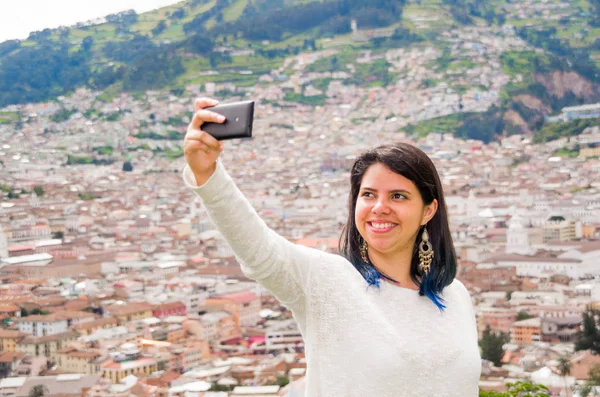 Joven chica latina tomar una selfie de con su teléfono en verano, detrás de una ciudad urbana. Concepto de vida urbana —  Fotos de Stock