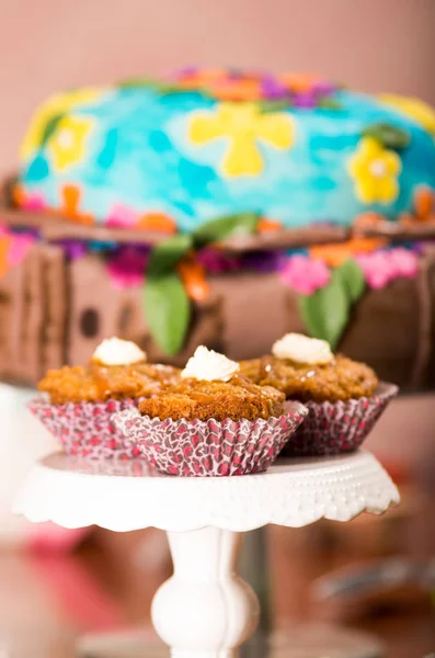 Läckra bruna färgade muffins med kolasås och grädde som topping, färgglad tårta i bakgrunden, konditorivaror koncept — Stockfoto