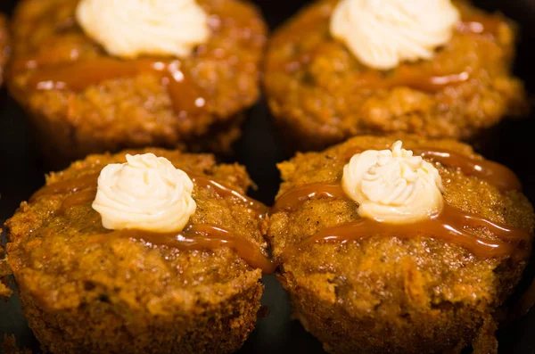 Deliziosi muffin di colore marrone allineati con caramello e crema di condimento, come visto dall'alto, concetto di pasticceria — Foto Stock