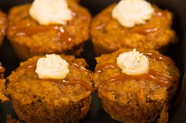 Deliziosi muffin di colore marrone allineati con caramello e crema di condimento, come visto dall'alto, concetto di pasticceria — Foto Stock