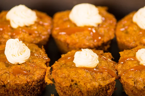 Deliziosi muffin di colore marrone allineati con caramello e crema di condimento, come visto dall'alto, concetto di pasticceria — Foto Stock