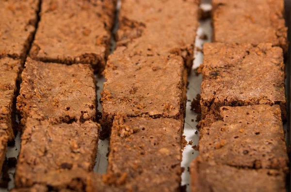 Deliziosi brownie al cioccolato di colore marrone allineati, pezzi quadrati visti dall'alto, taglierina per dolci in metallo utilizzata, concetto di pasticceria — Foto Stock