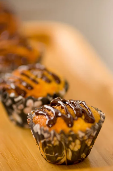 Вкусный ванильный кекс с шоколадным сиропом на деревянном фоне — стоковое фото