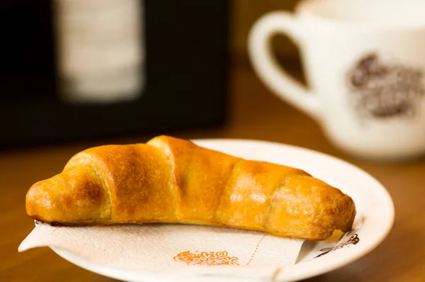 Deliciosos croissants frescos assados na placa com um fundo de madeira — Fotografia de Stock