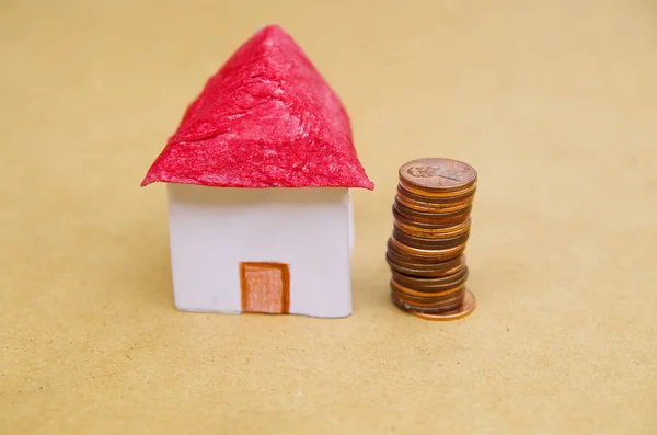 Small beautiful house with coins stacked in front of the housing model pretending: house prices, house buying, real estate, mortgage concept — Stock Photo, Image