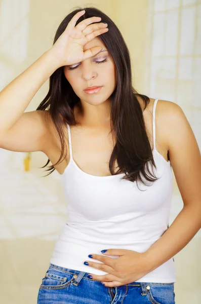 Young beautiful hispanic woman touching her belly with one hand and touching her head with her other hand, suffering menstrual period pain, female health concept — Stock Photo, Image