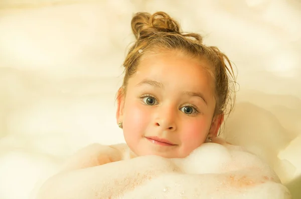 Mooi meisje poseren binnenkant van een bad met water en schuim in Bad — Stockfoto