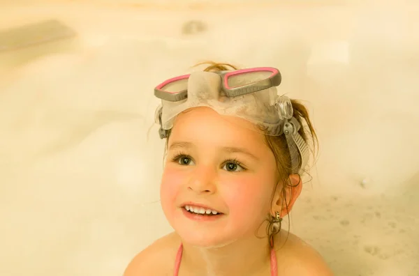 Close-up van een mooi meisje, spelen met water en schuim in Bad met behulp van een zwembroek en mooie duik zonnebril — Stockfoto