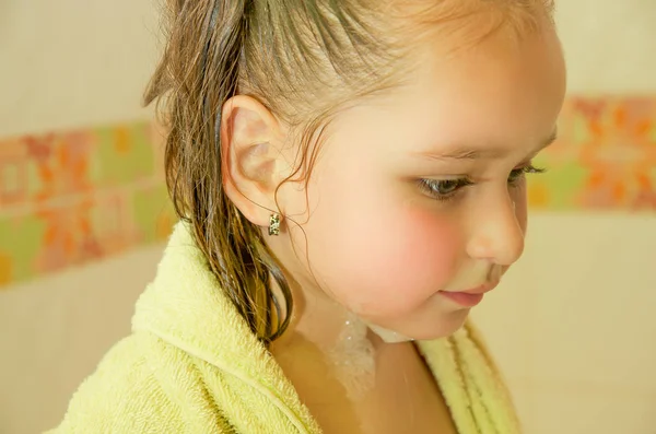 Little beautiful girl playing taking a shower in bath with a yellow Bathrobe — Stock Photo, Image