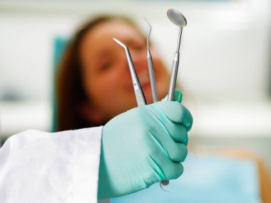 Doktor enstrümanlarını tutarken diş tedavisi diş hekimleri ofiste olan güzel bir kadın hasta