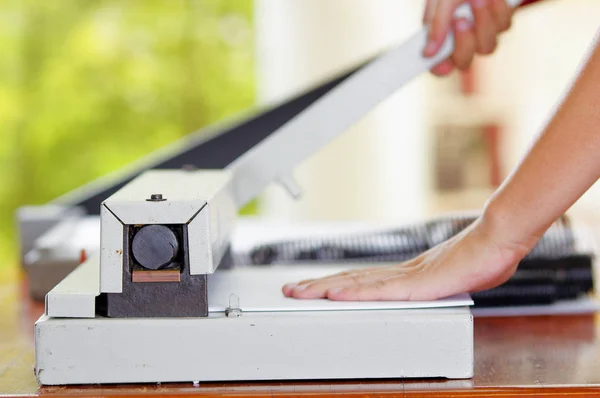 Omul folosind tăietor manual de hârtie pentru a tăia facturile imprimate în foile de hârtie, pe o masă de lemn, Lucrări de fabricație — Fotografie, imagine de stoc