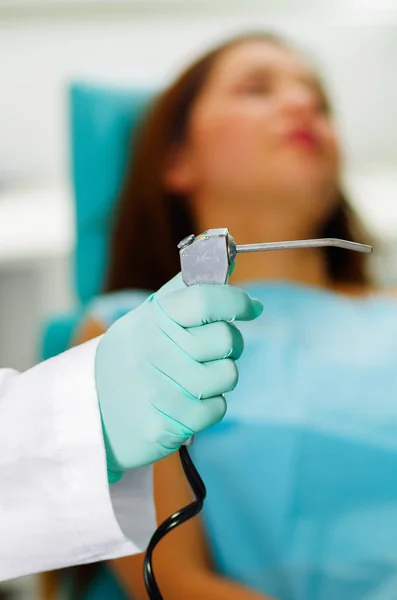Mujer hermosa paciente que recibe tratamiento dental en el consultorio de dentistas mientras el médico sostiene un instrumento —  Fotos de Stock