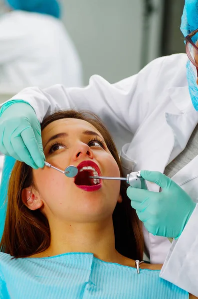 Gyönyörű nő beteg rendelkező fogászati kezelések, fogorvos irodájában. Nő, látogatás a fogorvos — Stock Fotó