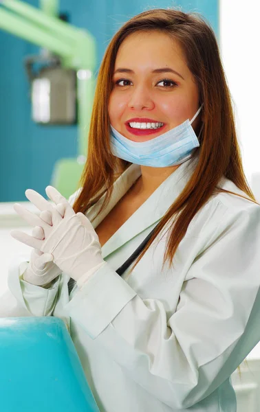 Bela mulher sorridente médico posando para a câmera enquanto ela está usando uma máscara cirúrgica em seu queixo — Fotografia de Stock