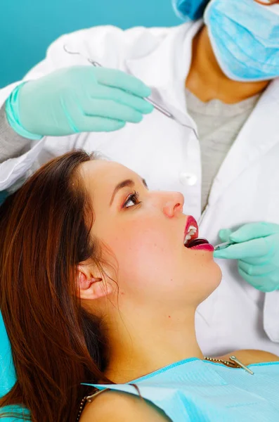 Mooie vrouw patiënt met tandheelkundige behandeling bij tandartsen kantoor. Vrouw haar tandarts te bezoeken — Stockfoto