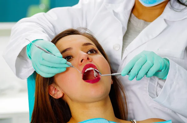 Hermosa paciente que recibe tratamiento dental en el consultorio de dentistas. Mujer visitando a su dentista —  Fotos de Stock