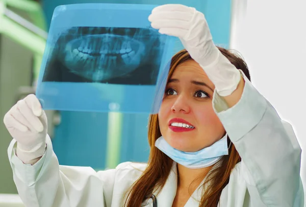 Прекрасная счастливая женщина-врач держит рентген и наблюдает за структурой зубов в кабинете стоматолога — стоковое фото