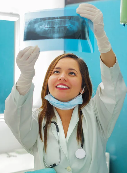 Прекрасная счастливая женщина-врач держит рентген и наблюдает за структурой зубов в кабинете стоматолога — стоковое фото
