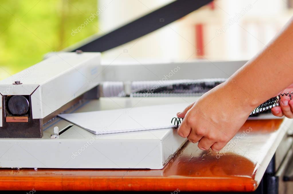 Man using manual paper cutter to cut the bills printed in the sheets of paper, on a wooden table, Manufacture work