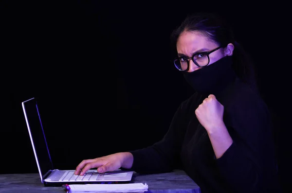 Портрет хакера з ноутбуком на темному тлі з використанням окулярів під час роботи — стокове фото