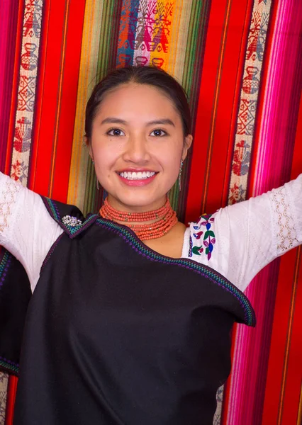 Prachtige Spaanse model dragen Andes traditionele kleding glimlachend en poseren voor de camera, kleurrijke stoffen achtergrond — Stockfoto