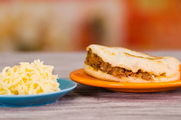 Arepas deliciosas tradicionales, aguacate de pollo rallado y queso cheddar y carne rallada en tierra negra de madera —  Fotos de Stock