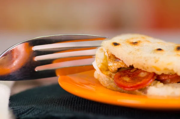 Primer plano de un delicioso arepas tradicionales, aguacate de pollo rallado y queso cheddar y carne rallada con un tenedor metálico —  Fotos de Stock