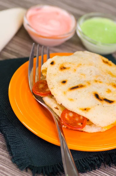 Primer plano de un delicioso arepas tradicionales, aguacate de pollo rallado y queso cheddar y carne rallada con un tenedor metálico —  Fotos de Stock