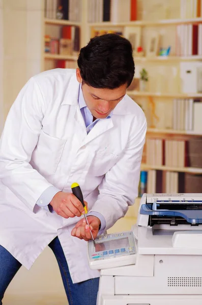 Красивый человек чинит ксерокс во время технического обслуживания с помощью отвертки — стоковое фото