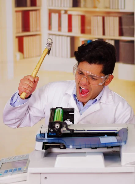 Bonito homem gritando enquanto ele está consertando um toner durante a manutenção usando um martelo — Fotografia de Stock