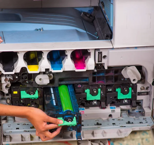 Fecho de uma mulher que fixa uma fotocopiadora durante a manutenção, segurando um toner — Fotografia de Stock