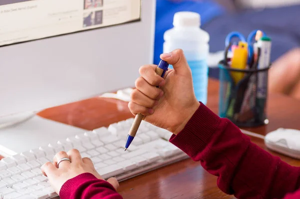 Närbild av en kvinnlig hand som håller en penna i ett skrivbord med en dator. mixtra koncept — Stockfoto