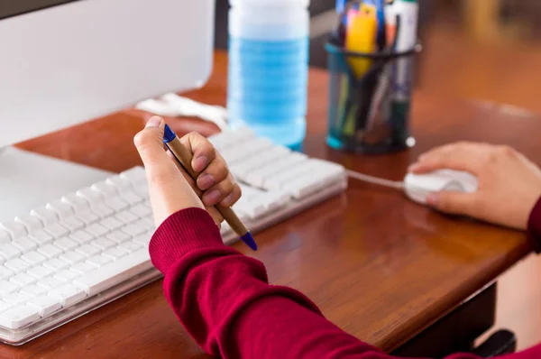 Närbild av en kvinnlig hand som håller en penna i ett skrivbord med en dator. mixtra koncept — Stockfoto