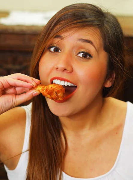 Närbild av en skönhet kvinna i en restaurang äter en läcker kycklingvingar — Stockfoto