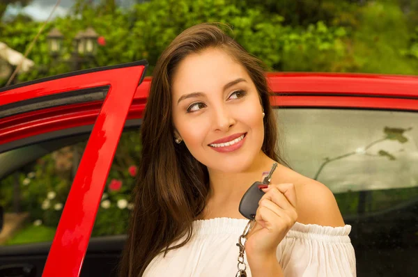 Beautiful sexy young woman holding her keys and smiling and a red car behind — Stock Photo, Image