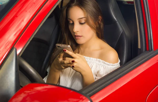 Schöne Frau in rotem Auto SMS in ihr Handy — Stockfoto
