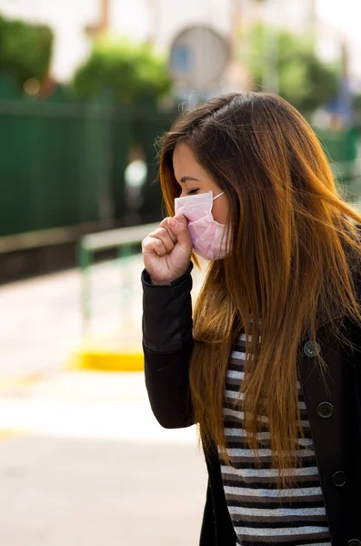Mladá žena s ochrannou maskou, pocit špatného na ulici ve městě s znečištění ovzduší, město pozadí — Stock fotografie