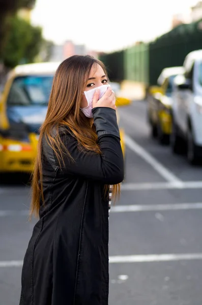 Koruyucu maske takıyor ve hava kirliliği, sahip şehirde sokakta eliyle ağzını kapsayan genç kadın trafik arka plan — Stok fotoğraf