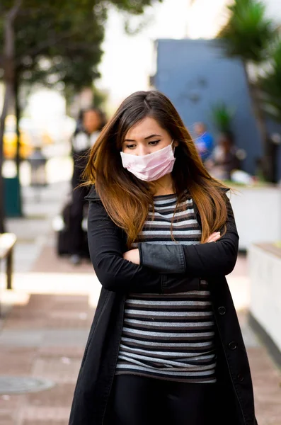 Sad young woman with protective mask feeling bad on the street in the city with air pollution, city background — Stock Photo, Image