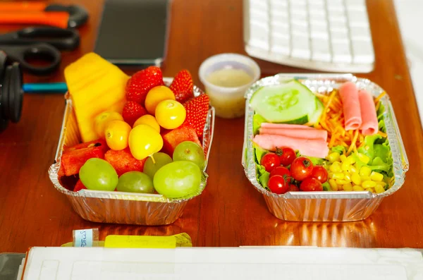 Deliciosa ensalada de estilo mediterráneo con jamón y ensalada de frutas en caja de aluminio sobre mesa de madera — Foto de Stock