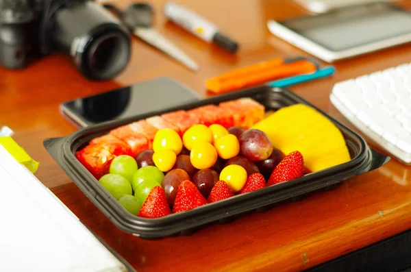 Primer plano de un desayuno saludable, ensalada de frutas envasadas en caja de plástico sobre una mesa de madera —  Fotos de Stock