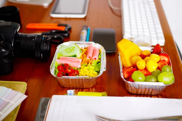 Köstliche mediterrane Art frischer Salat mit Schinken und Obstsalat auf Aluminiumbox umgeben von Büromaterial, Pause im Büro — Stockfoto