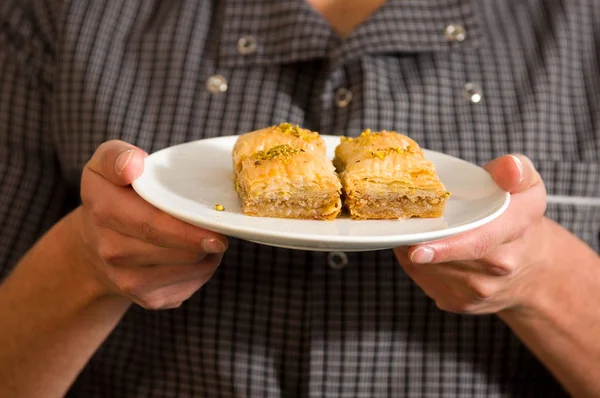 Man holding a delicious traditional turkish food baklava with pistachio in his hands — Stock Photo, Image