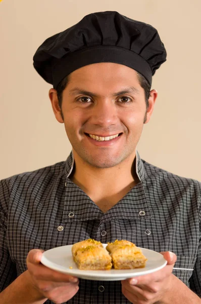 Un homme souriant tenant un délicieux baklava traditionnel turc avec des pistaches à la main — Photo