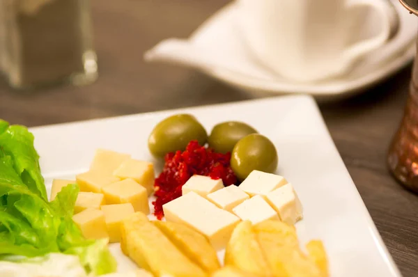 Primo piano di un delizioso luch fresco mediterraneo con lattuga, formaggio, patate fritte e alcune olive su un tavolo di legno — Foto Stock