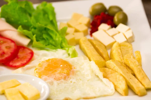 Gros plan d'une délicieuse luche méditerranéenne fraîche avec œuf, laitue, jambon tomate, cheesse, pomme de terre frite et olives somes sur une table en bois — Photo