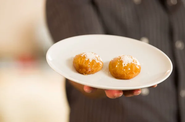 L'homme tient un délicieux sekerpare de dessert turc avec de la poudre de noix de coco — Photo