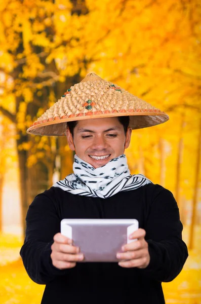 秋の背景に彼の手で彼のアプリを押しアジア円錐帽子を身に着けているハンサムなヒスパニック系の若いビジネス男の肖像 — ストック写真